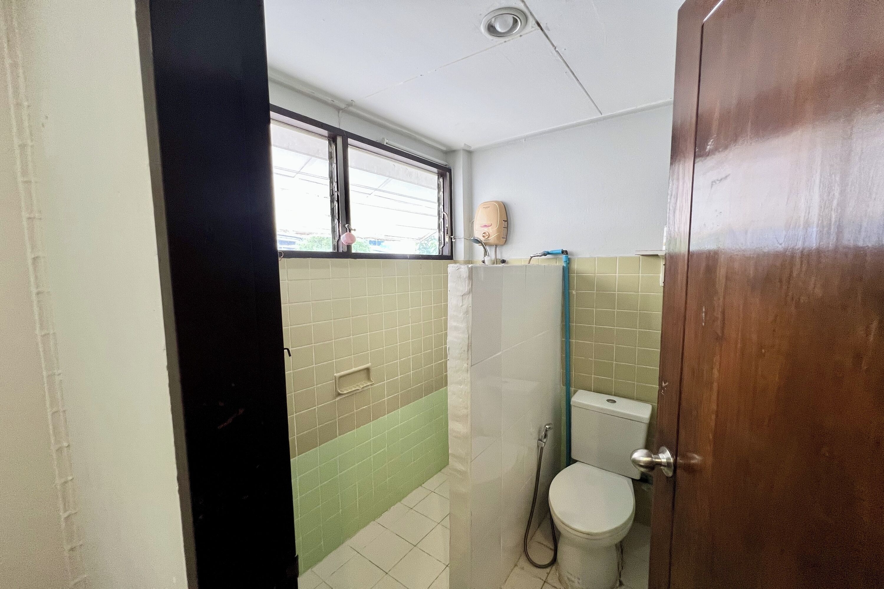 Une salle de bain avec des toilettes, une douche et une fenêtre.