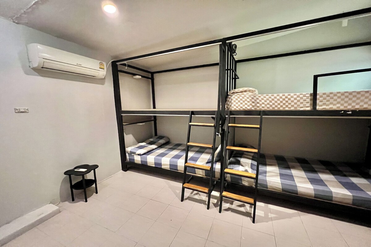 Quarto com beliche, uma mesinha e ar condicionado.