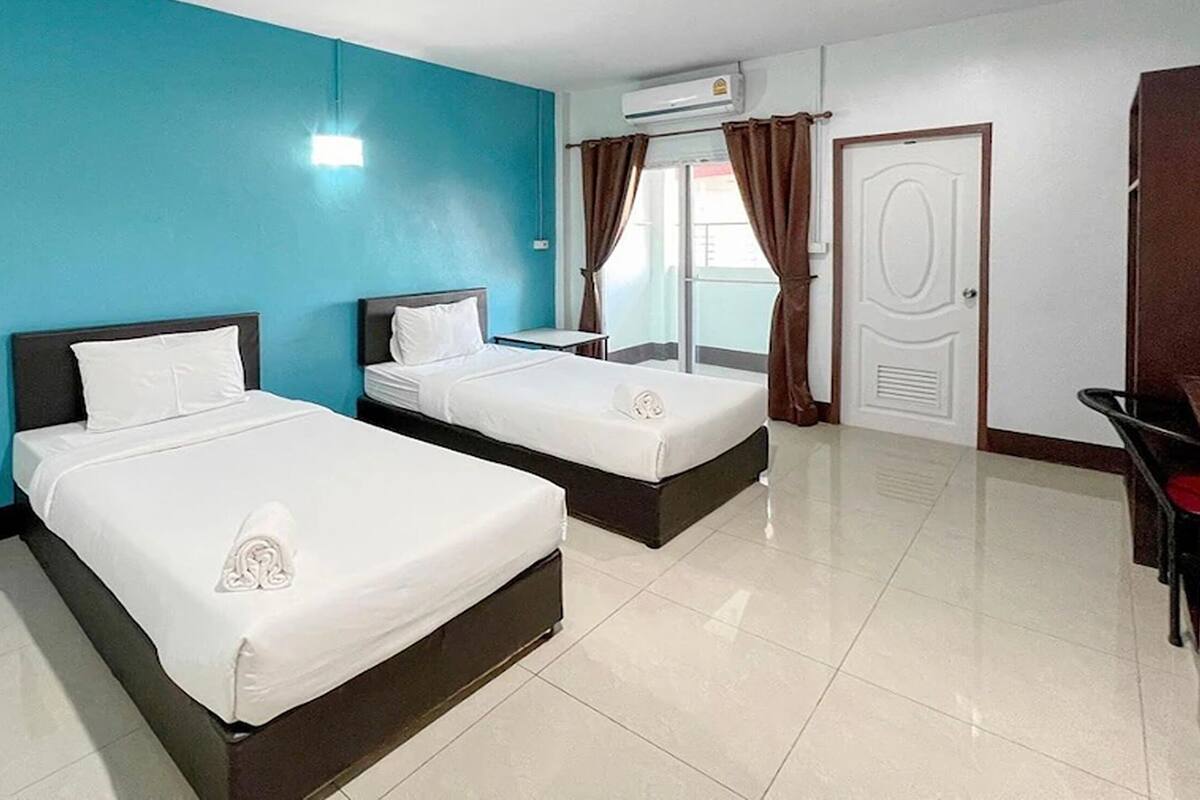 A hotel room with two beds, a desk, and a door.