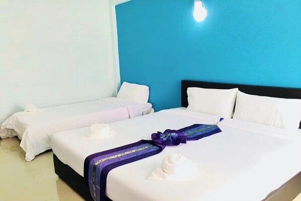 A hotel room with two beds, each with white linens and pillows. The room has a blue accent wall and a light-colored floor. - Chat House Chiang Rai (Chiang Rai)