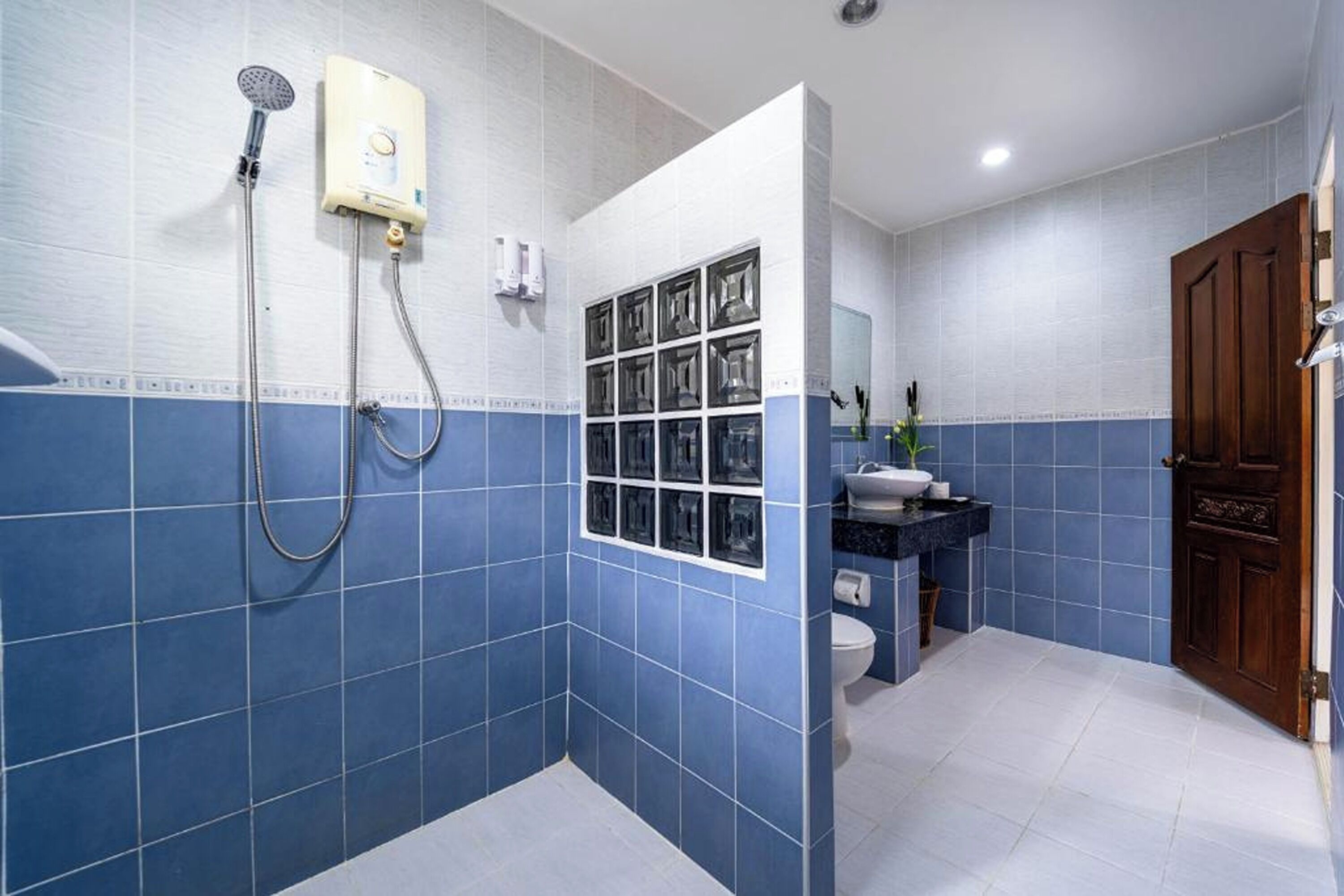 A bathroom with blue and white tiles, a shower, a toilet, and a sink.