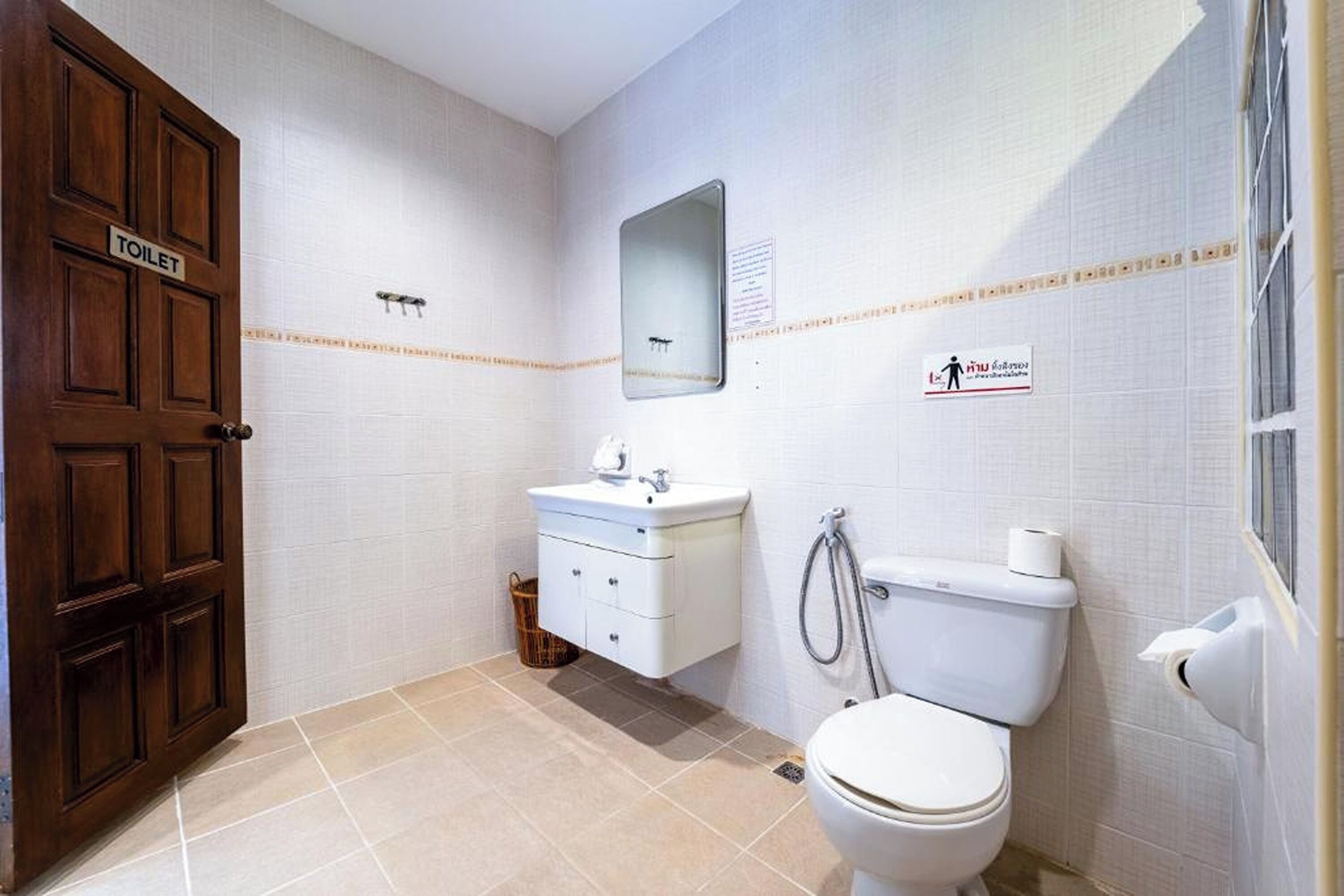A bathroom with a toilet, sink, and mirror.