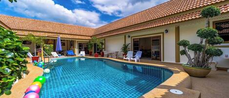 Una piscina al aire libre, sombrillas, sillones reclinables de piscina