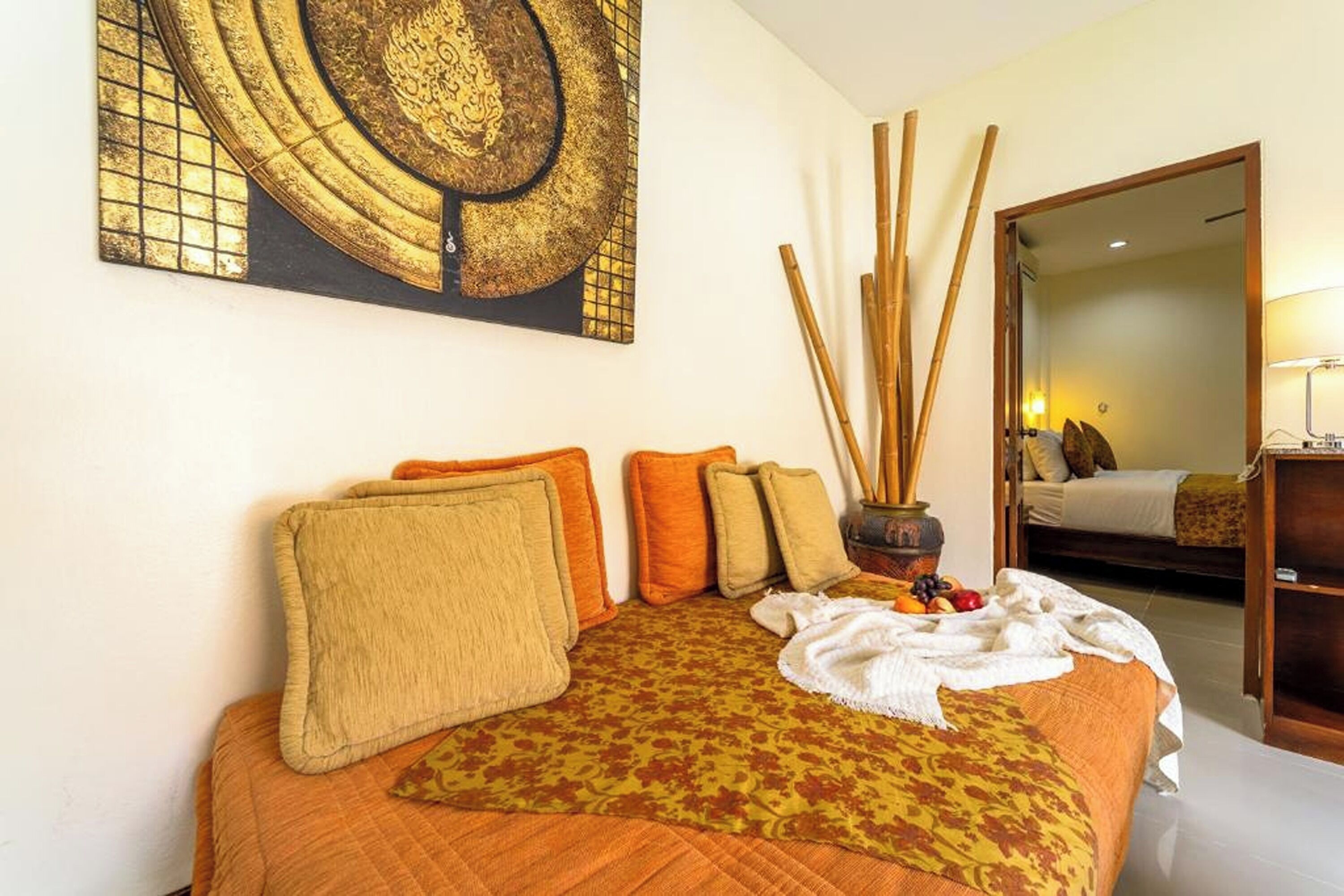 Une chambre d’hôtel avec un grand lit, plusieurs oreillers, un élément décoratif mural et un miroir qui reflète une autre pièce.