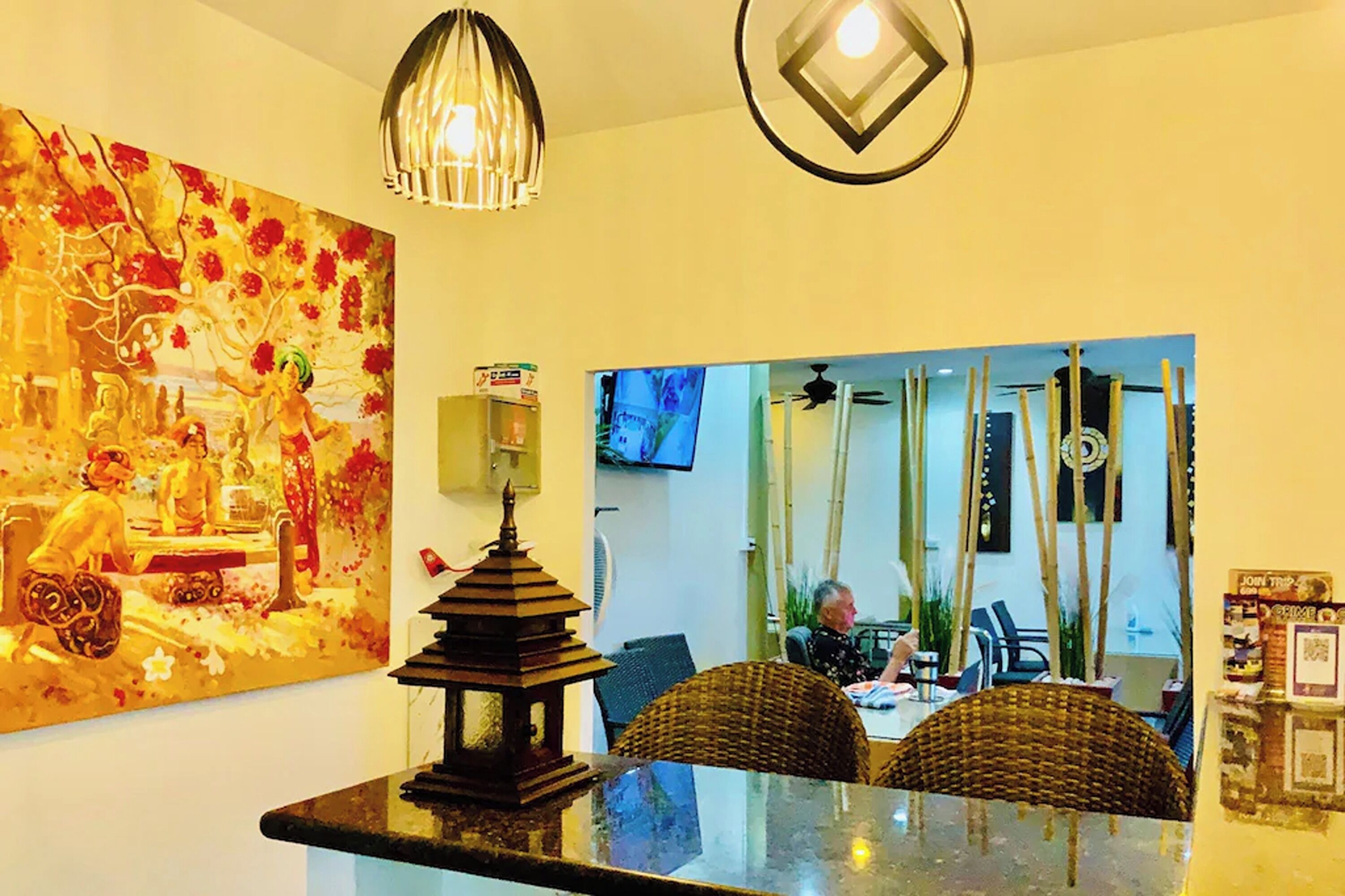 A dining area with a table, chairs, a decorative lantern, and a large painting on the wall.