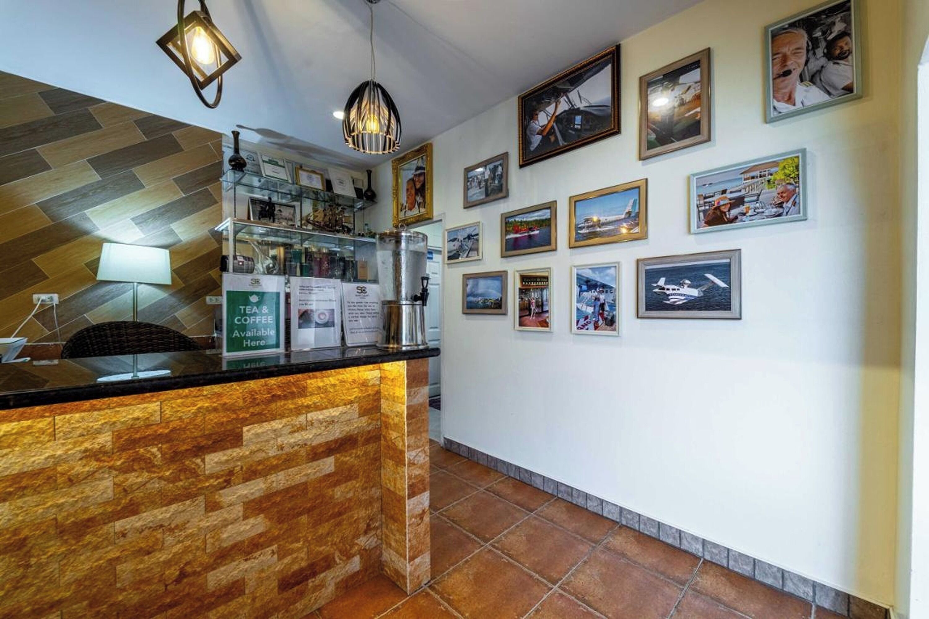 A reception area with a coffee station, framed pictures on the wall, and a herringbone-patterned counter.