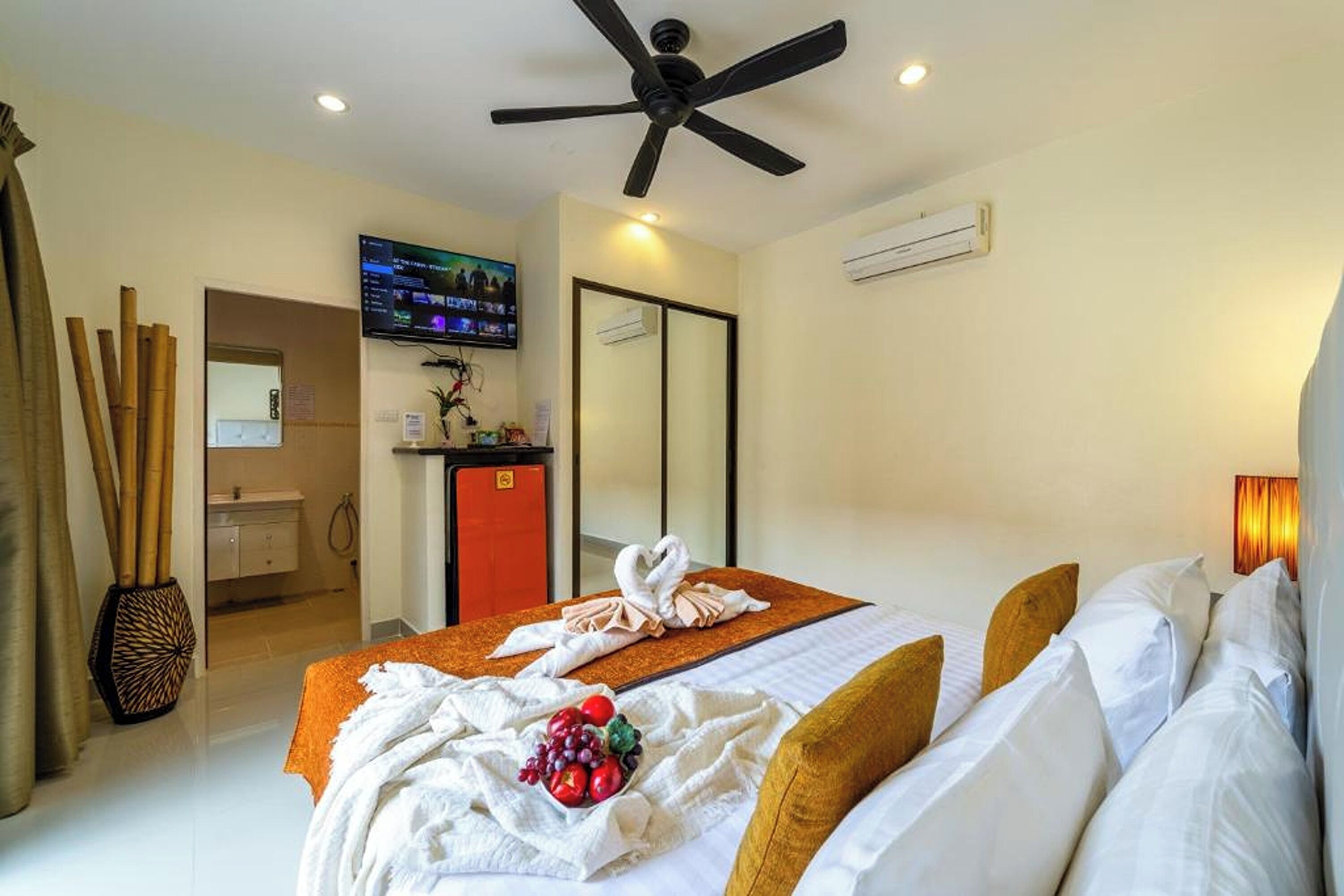A hotel room with a bed, a ceiling fan, a TV, and a bathroom visible through an open door.