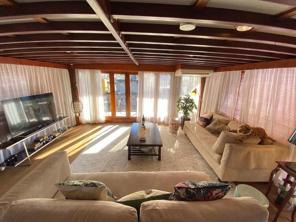 Una sala de estar con sofá, televisor y planta.