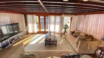 Una sala de estar con sofá, televisor y planta.
