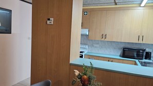 Una cocina compacta con armarios de madera, un microondas y una cafetera.