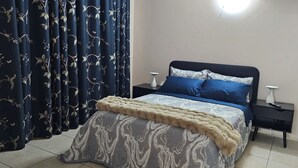 Un dormitorio con una cama, dos mesitas de noche y una cortina de estampado floral.