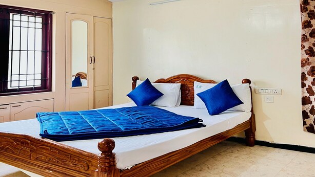 A room with a bed, a wardrobe, a window with bars, and a wall-mounted light fixture. - Caron Niron Two Bedroom Villa (Kodaikanal)
