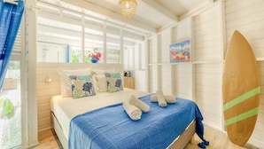 A bedroom with a bed, pillows, a surfboard, and a window.