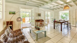 A spacious living room with a leather sofa, a coffee table, and a dining area with a table and chairs.