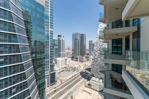 A high-rise building with a modern glass facade, a parking lot, and a clear view of the cityscape. - 2-BR Missoni Luxury with Stunning Lake View (Dubai)