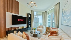 A modern living room with a flat-screen TV, a sofa, a coffee table, and a bookshelf.
