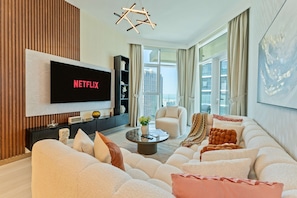 A modern living room with a flat-screen TV, a sofa, a coffee table, and a bookshelf.