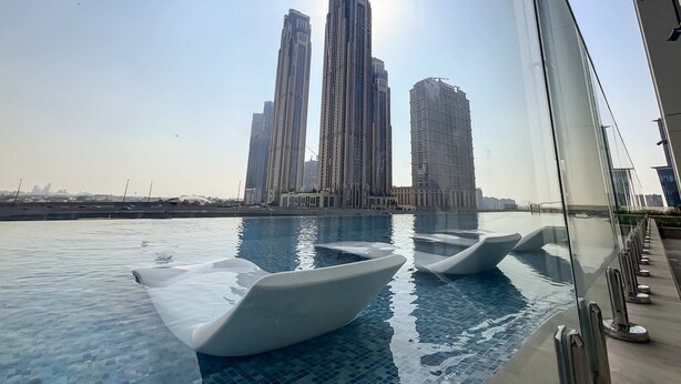A swimming pool with clear water, surrounded by tall buildings.