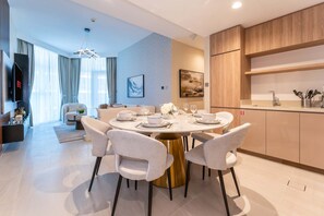 A modern dining area with a round table, white chairs, and a gold base. - 2-BR Missoni Luxury with Stunning Lake View (Dubai)