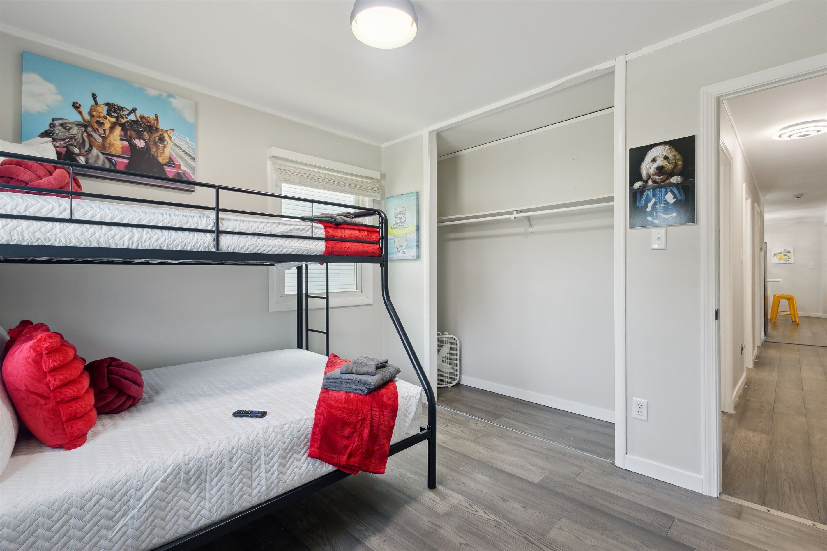 A bunk bed room with a painting of dogs on the wall, a small heater, and a door leading to another room.