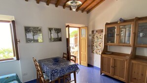 A dining area with a table and chairs, a wooden cabinet with glass doors, and a door leading outside.