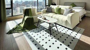 A modern living room with a large window, a sofa set, a coffee table, and a patterned rug. - Yoki shimao international apartment (Beijing)