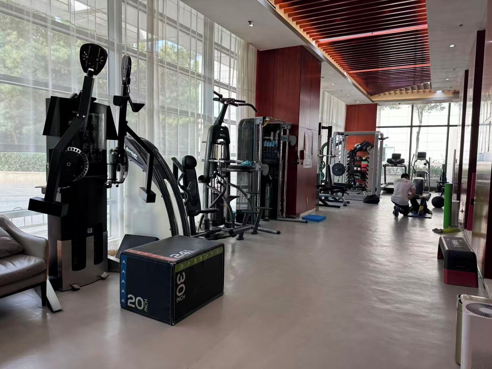 A gym with exercise equipment, large windows, and a modern interior design.