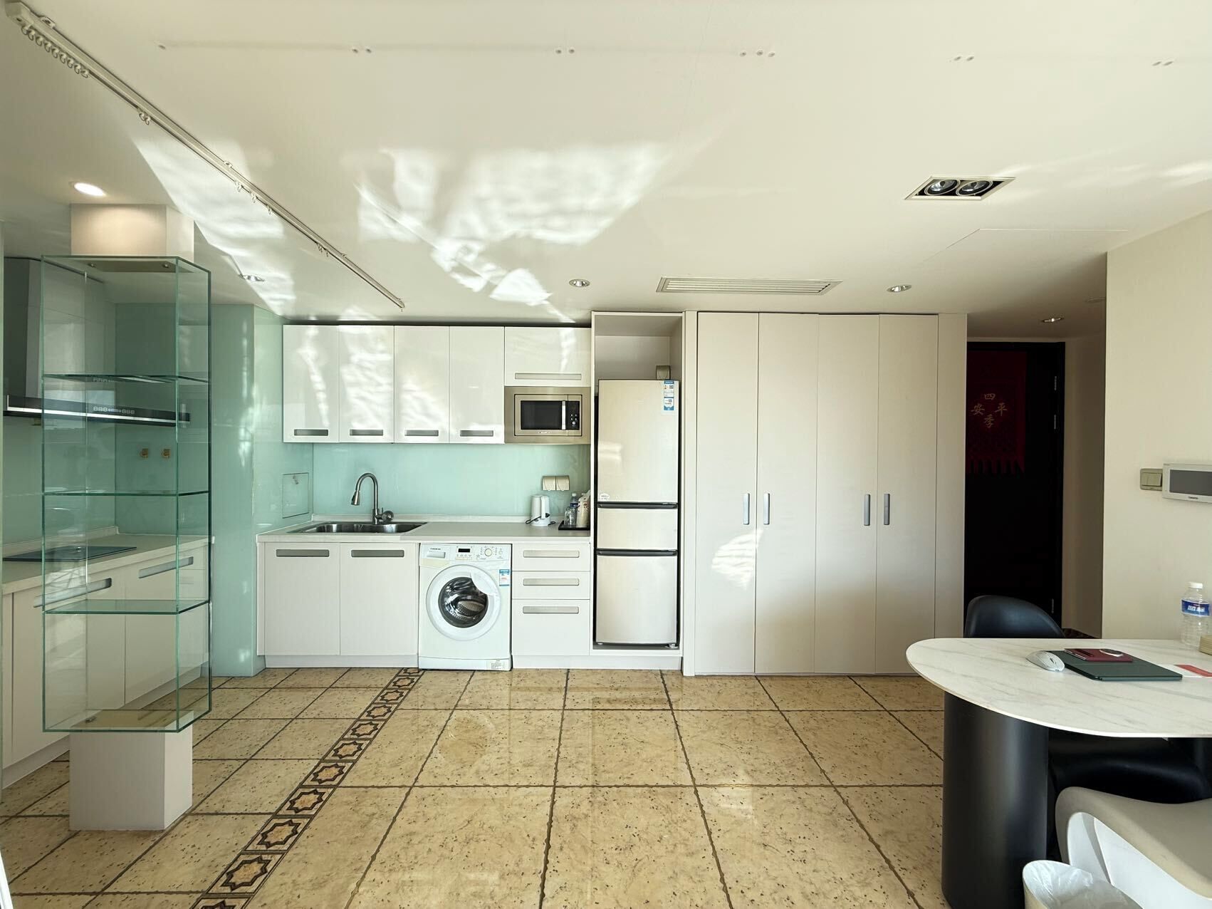 A modern kitchen with a washing machine, microwave, and a dining area with a table and chairs.
