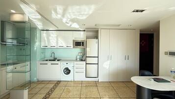 A modern kitchen with a washing machine, microwave, and a dining area with a table and chairs.