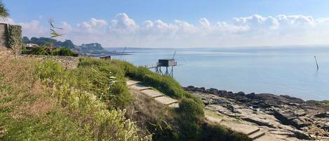 Eine Küstenlandschaft mit einem Steinweg, der zu einer Aussichtsplattform mit Blick aufs Meer führt.