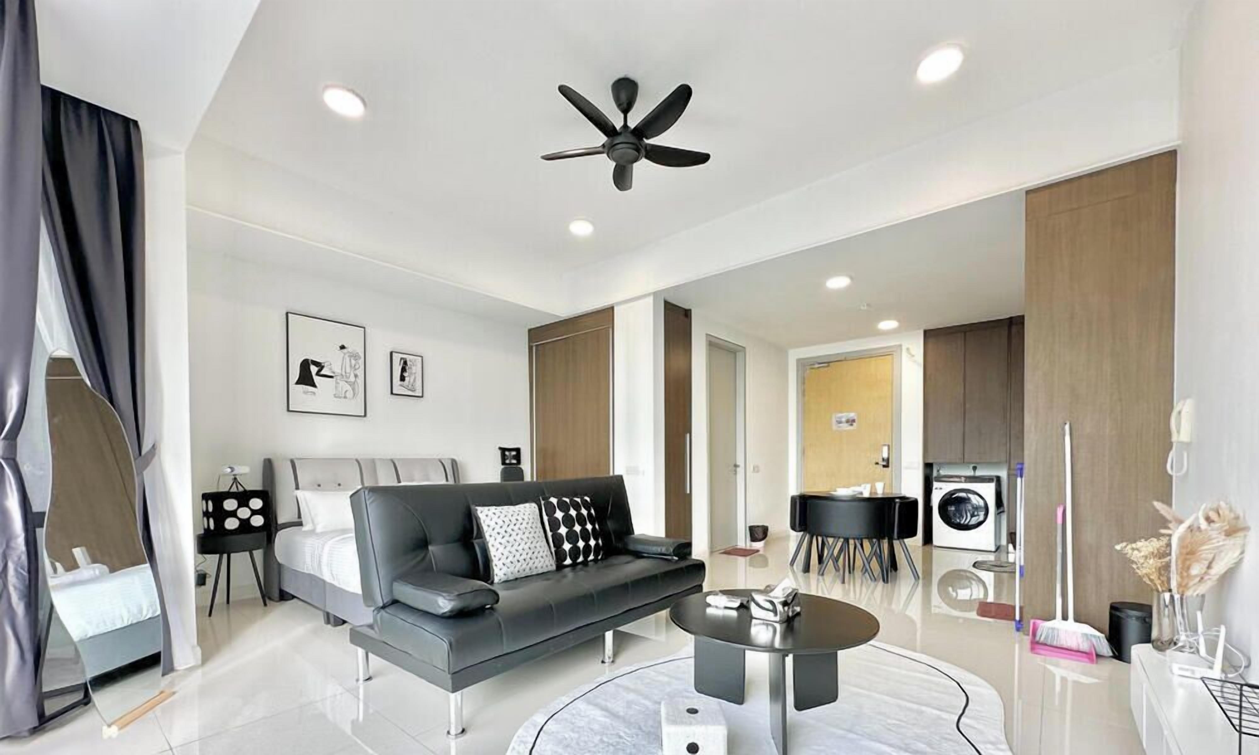 A modern hotel room with a bed, sofa, coffee table, and a ceiling fan.