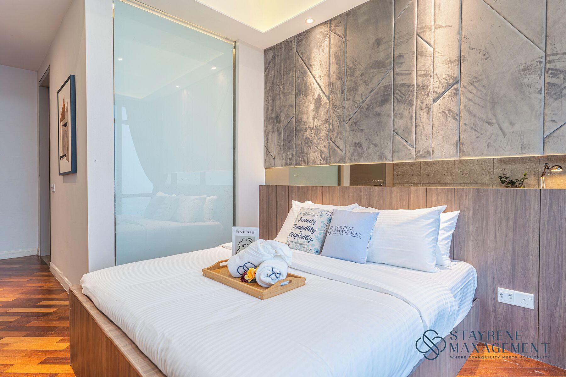 A hotel room with a large bed, a glass partition, and a marble wall.