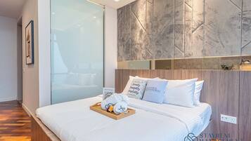 A hotel room with a large bed, a glass partition, and a marble wall.