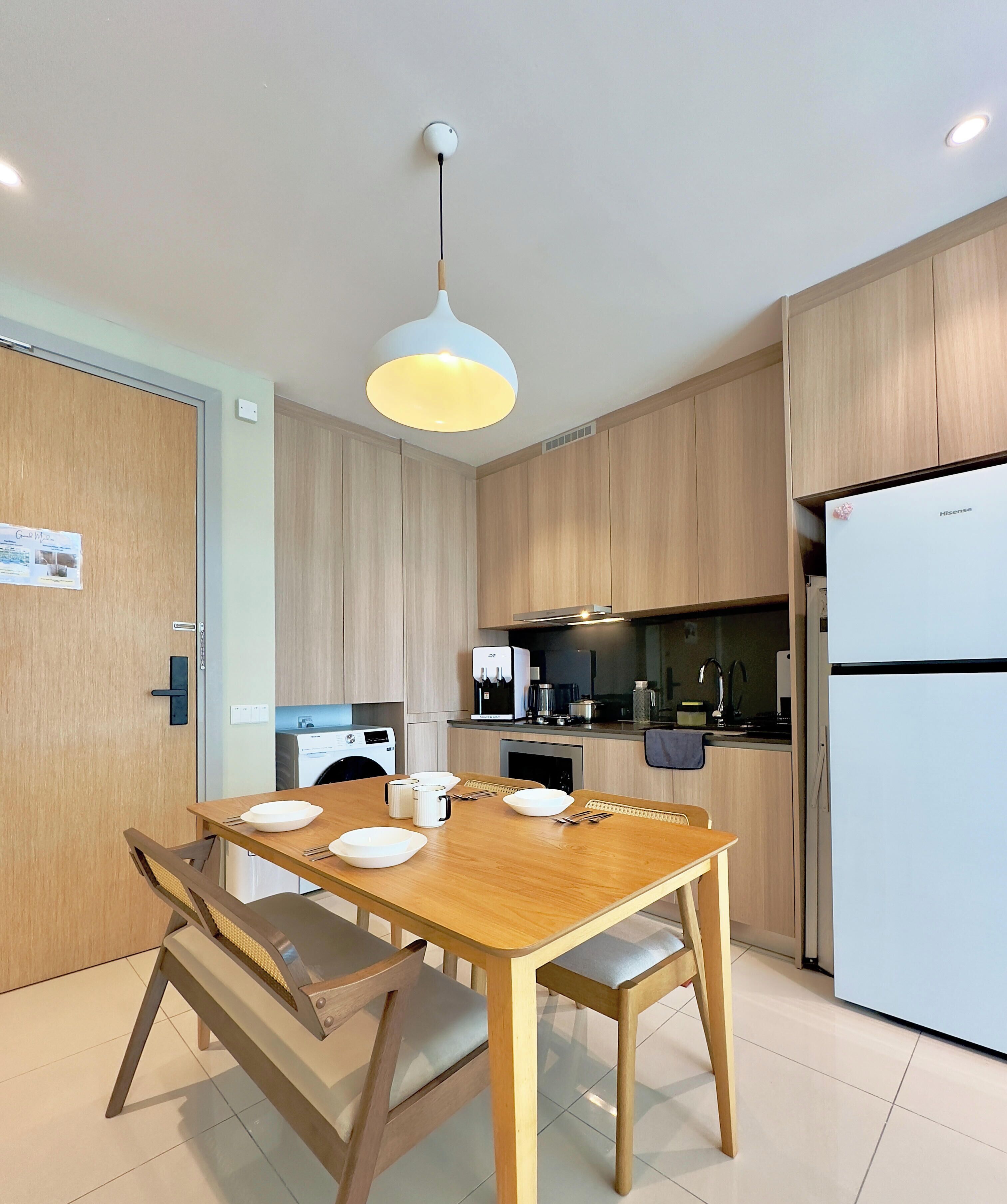 A modern kitchen with wooden cabinets, a dining table with chairs, a built-in oven, and a refrigerator.