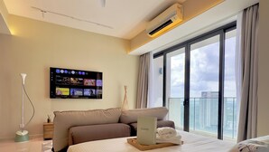 Een moderne hotelkamer met een groot bed, een flatscreen televisie aan de muur en een balkon met uitzicht over de stad.