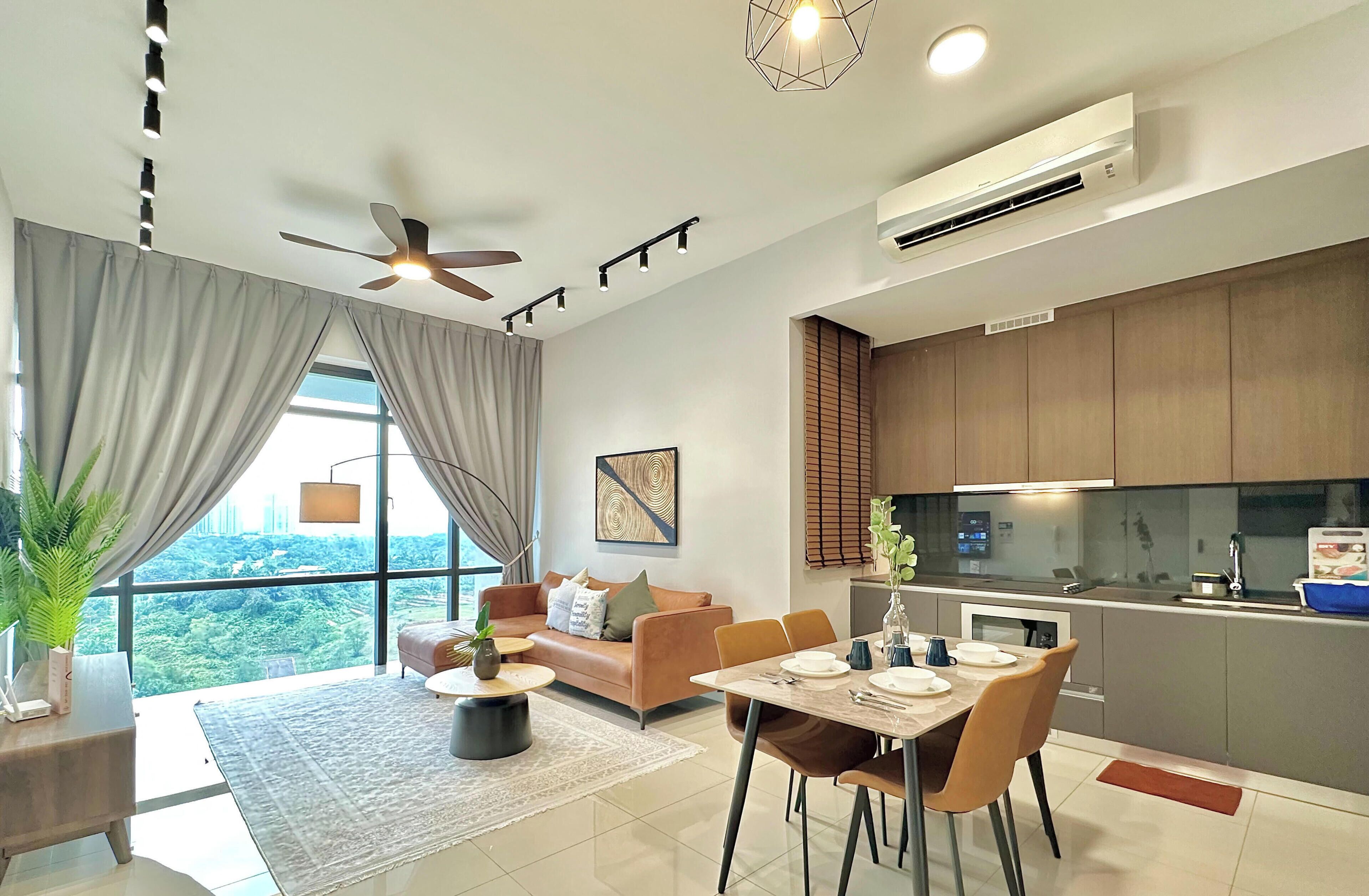 A modern living room with a sofa, dining table, and chairs. There is a ceiling fan, an air conditioning unit, and a large window with curtains.