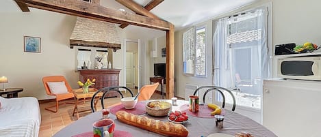 A cozy dining area with a table set for breakfast, featuring bread, fruit, and a mug.