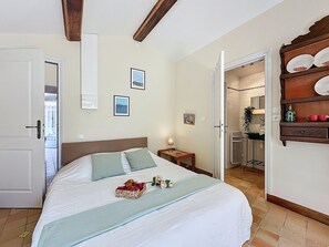 Ein Schlafzimmer mit einem Bett, einem Nachttisch, einer Holzregal mit Geschirr und einem durchgegangenen Tür sichtbaren Badezimmer.