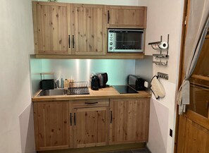 Une cuisine compacte avec des meubles en bois, un four encastré et un évier.