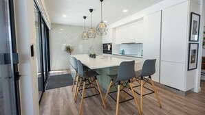 A modern kitchen with a central island, white cabinetry, and pendant lighting.