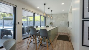 A modern kitchen with a large island, wooden flooring, and pendant lighting.