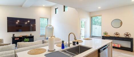 A modern kitchen with a large island, built-in appliances, and a flat-screen TV.