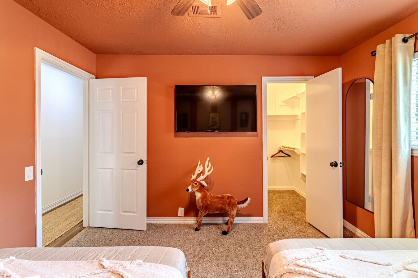 A room with two beds, a deer's head sculpture, and a mirror on the wall.
