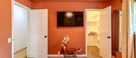 A room with two beds, a deer's head sculpture, and a mirror on the wall.