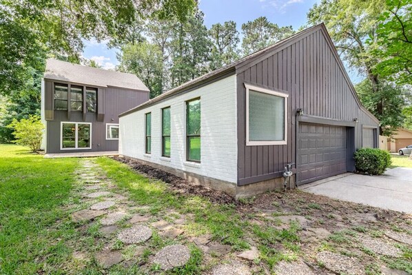 A two-story house with a garage, a paved driveway, and a well-maintained lawn.
