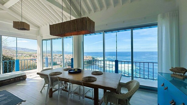 Een eetgedeelte met uitzicht op zee, een balkon en een modern interieur.