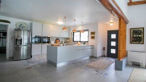 A modern kitchen with a central island, stainless steel appliances, pendant lighting, and a patterned floor. - Villa Sun and Sea | Pool n' 2min walk to the Beach (Ponta Delgada)