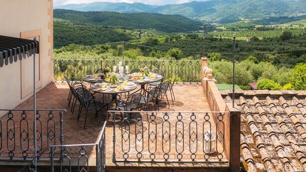 Une terrasse avec une table préparée pour le petit-déjeuner, offrant une vue sur un paysage montagneux.