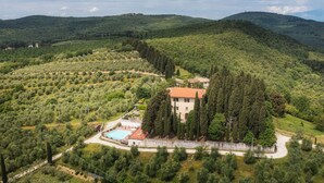 Une villa entourée d’oliveraies et de cyprès, dotée d’une piscine et bordée d’un chemin sinueux.