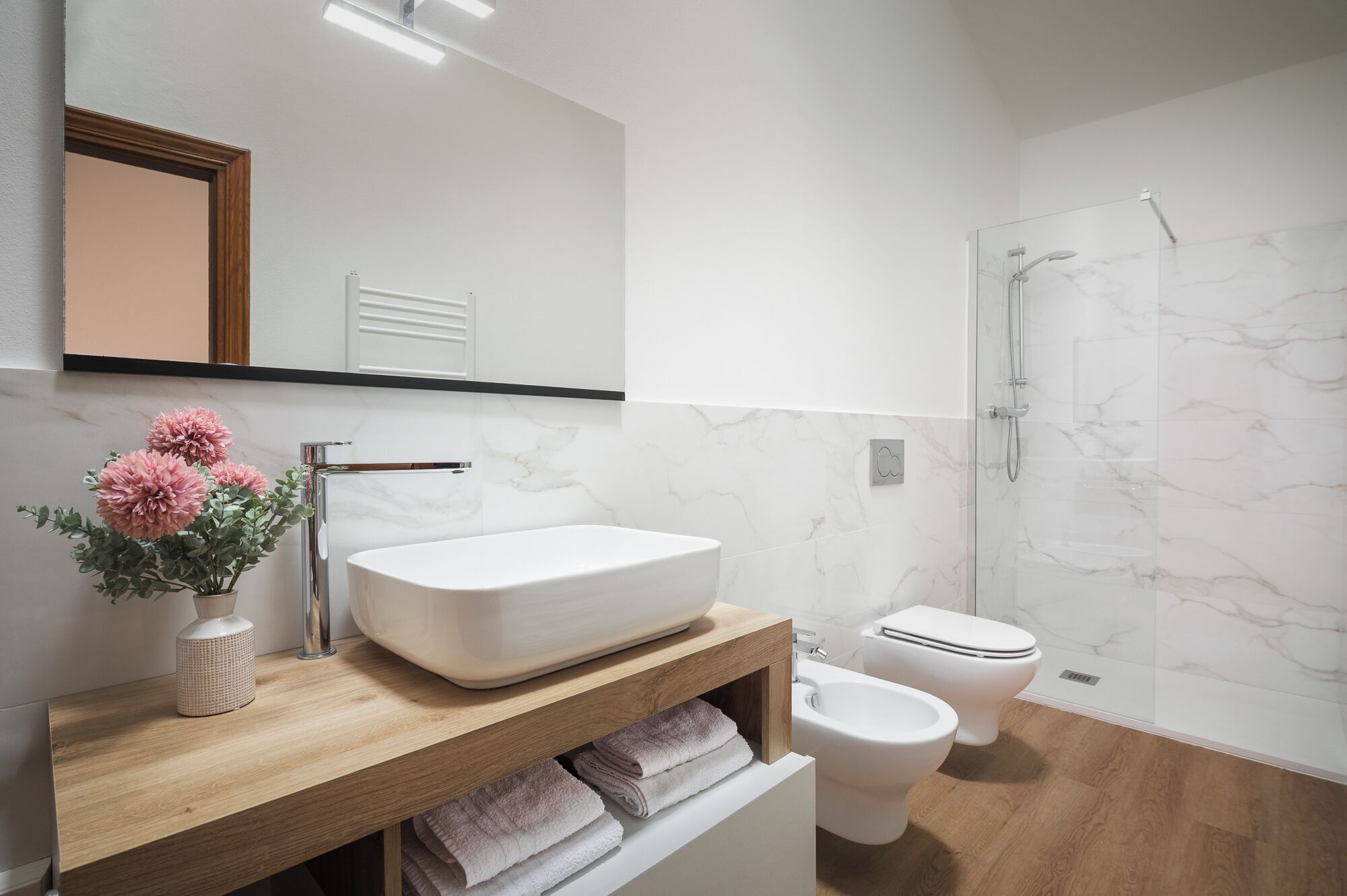 Een moderne badkamer met een wit wastafel, toilet en douche.